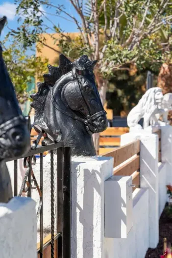 A bold black horse head sculpture adorns the gate.