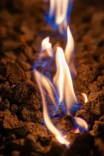 Close-up of a fire pit with glowing flames over lava rocks.