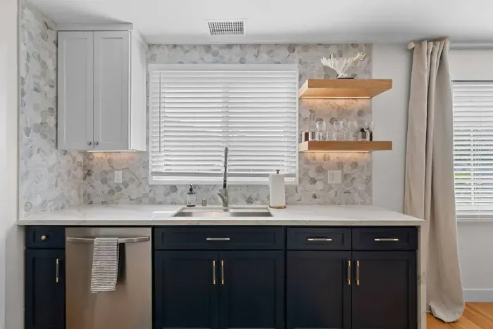Modern kitchen with navy cabinets and hexagonal backsplash.