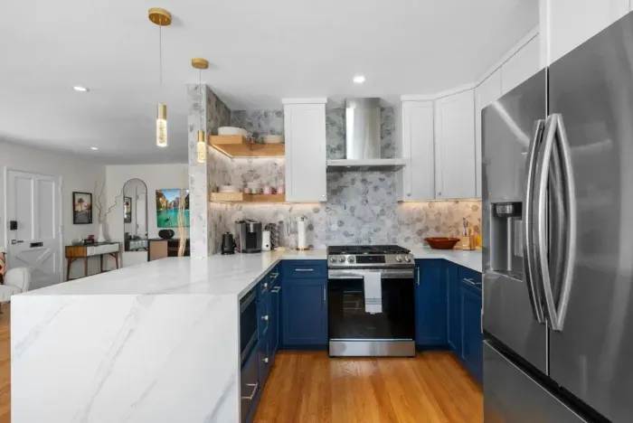 Modern kitchen blends navy cabinets, marble countertops, and warm wood tones for a stylish, inviting space.