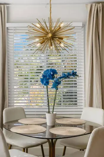 Elegant dining setup with a statement chandelier and vibrant floral touch.