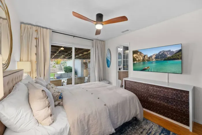 Cozy bedroom with soft neutrals, a modern fan, and seamless indoor-outdoor flow.