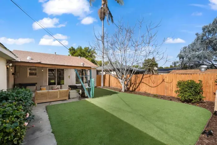 A cozy backyard retreat with lush artificial turf and inviting patio seating—ideal for outdoor gatherings!