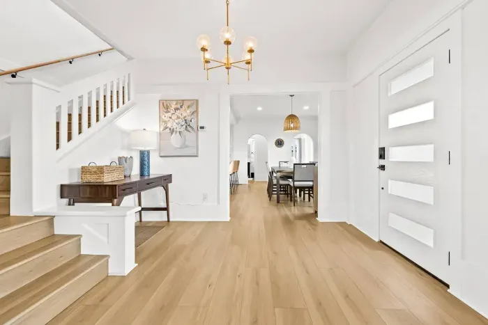 Open entryway with wood floors leading to dining and kitchen.