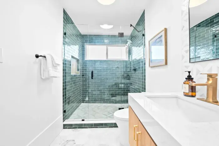 Modern bath with walk-in shower and green tile.
