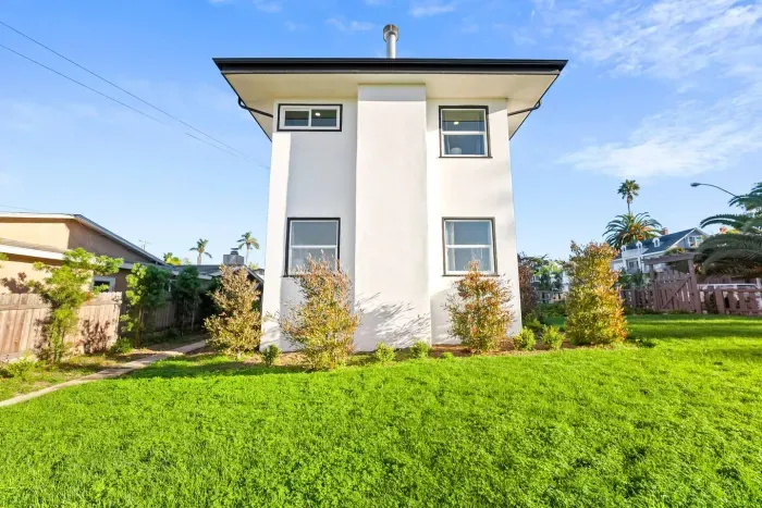 Side view of the home with tall windows and green lawn.