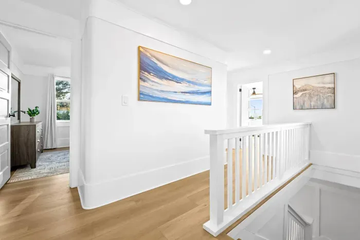 Sunny upstairs hallway with modern artwork.