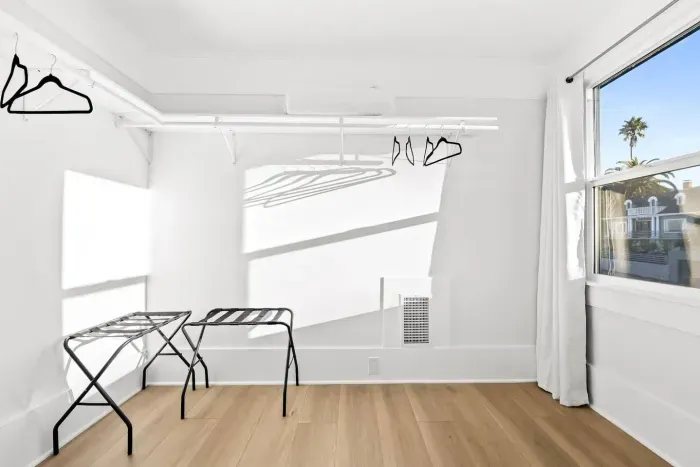 Open closet and luggage rack with bright lighting.