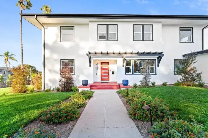 Front exterior with landscaped walkway and bold red door.
