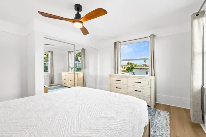 Bright bedroom with large windows and ceiling fan.