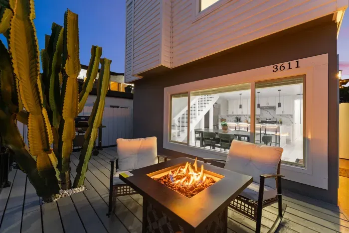 Stylish patio with fire pit, cactus, and window to a sleek open kitchen.
