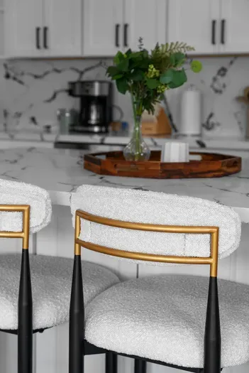 Sleek marble island, plush barstools, and a coffee-ready setup.
