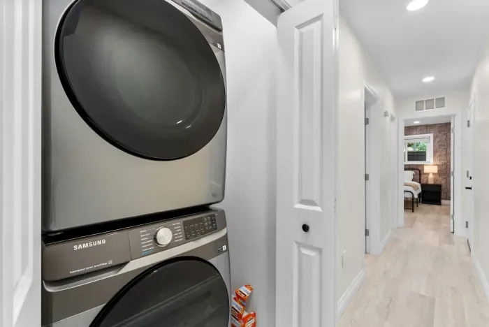 In‑unit Samsung washer & dryer in bright hall, steps from cozy bedroom