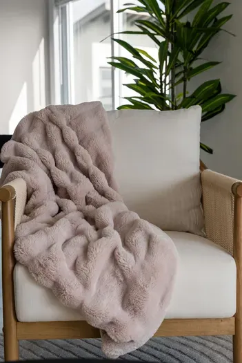 Sunlit reading nook: plush throw on modern, comfy armchair
