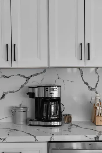 Modern coffee station on marble counters with knives and storage