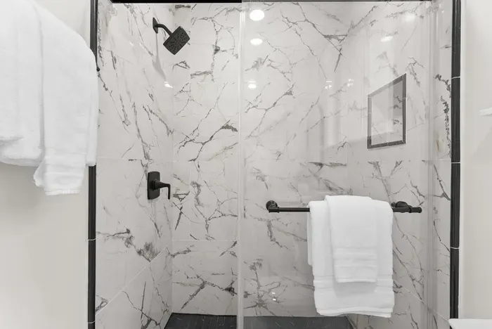 Sleek marble walk-in shower with rainfall head and plush towels