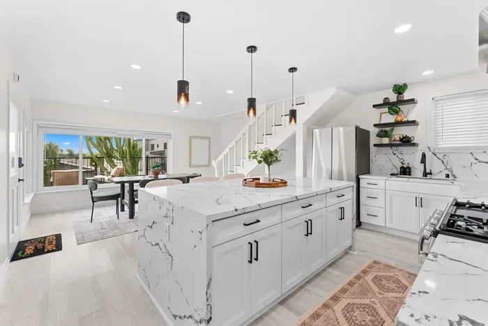 Bright chef’s kitchen w/ waterfall island, stainless appliances & patio access