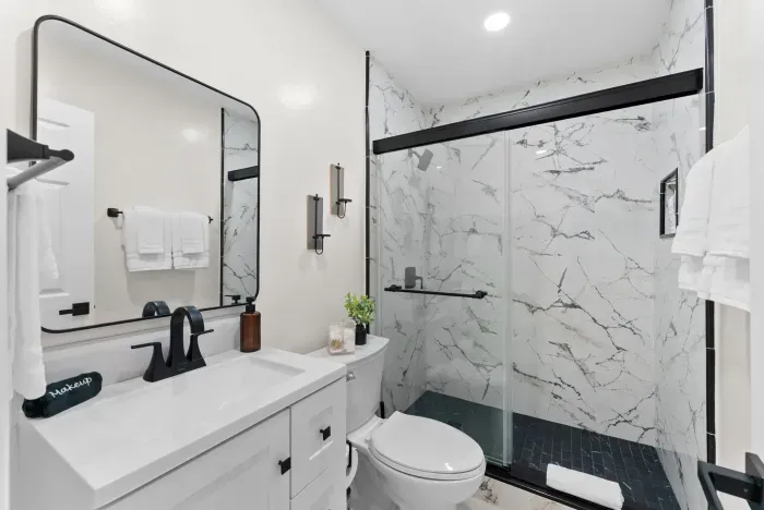 Sleek bath with marble shower, black fixtures, and plush towels