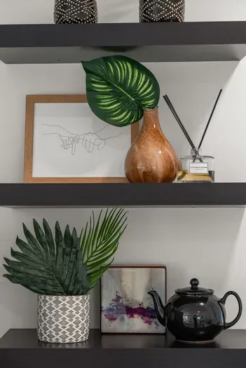 Stylish floating shelves with art, greenery, and cozy tea accents