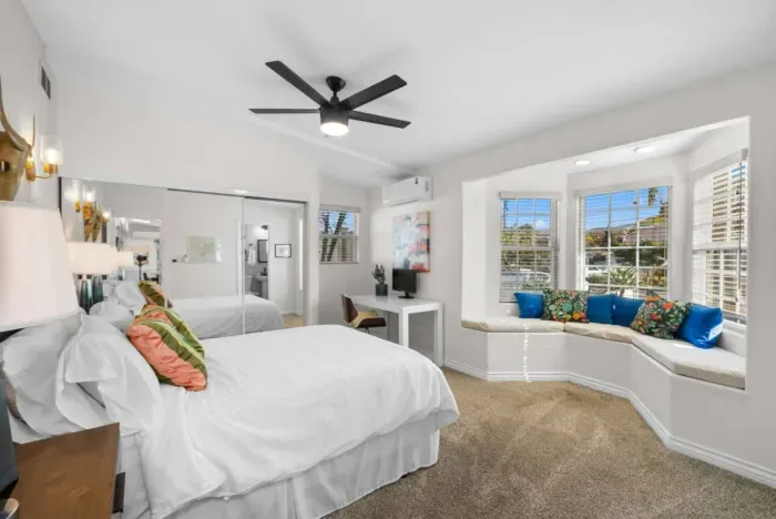 A spacious and stylish bedroom with a cozy window nook, perfect for relaxing or working.