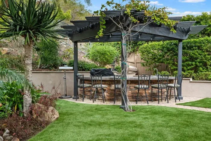 Outdoor kitchen with six bar stools, BBQ and a sink