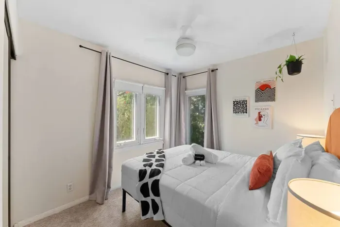 Crisp white bedroom with cozy accents and garden views