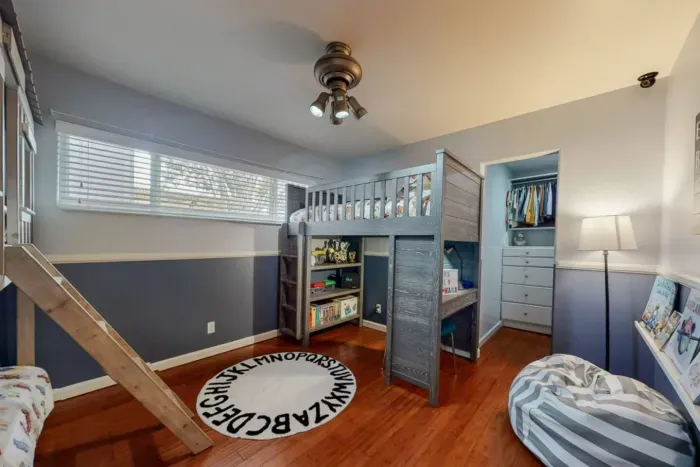 Fun kids’ room with loft bed, slide, cozy reading nook, and plenty of storage.