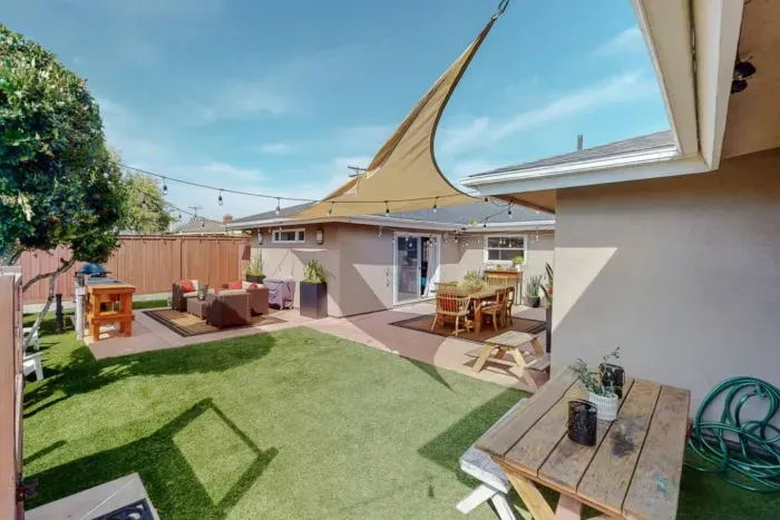Spacious backyard with shade sail, lounge area, and outdoor dining space.