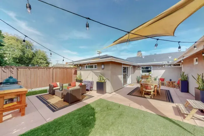High-end patio furniture, a private gas grill, and a separate alfresco dining area under ambient string lights