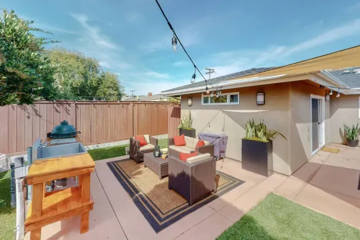 Cozy backyard oasis with seating, grill, and string lights for relaxing nights.