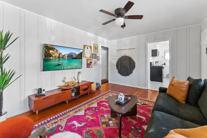 Living room showing comfy seating, a large TV, and bright décor that makes the space feel lively and inviting.