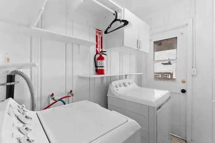 A convenient laundry room featuring a full washer and dryer plus shelving for easy organization.
