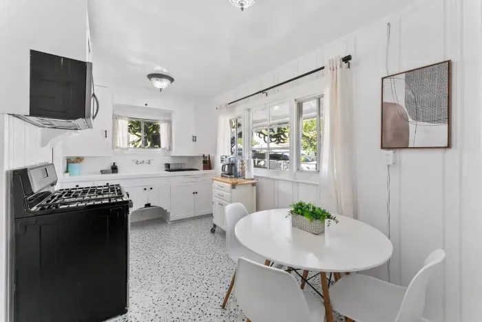 A cheerful, sunlit kitchen with vintage charm, offering ample counter space and a cozy dining nook.
