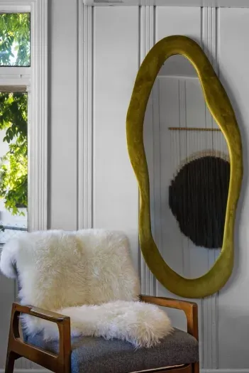 Stylish corner with a sculptural mirror and a plush sheepskin chair—perfect for relaxing or getting ready.