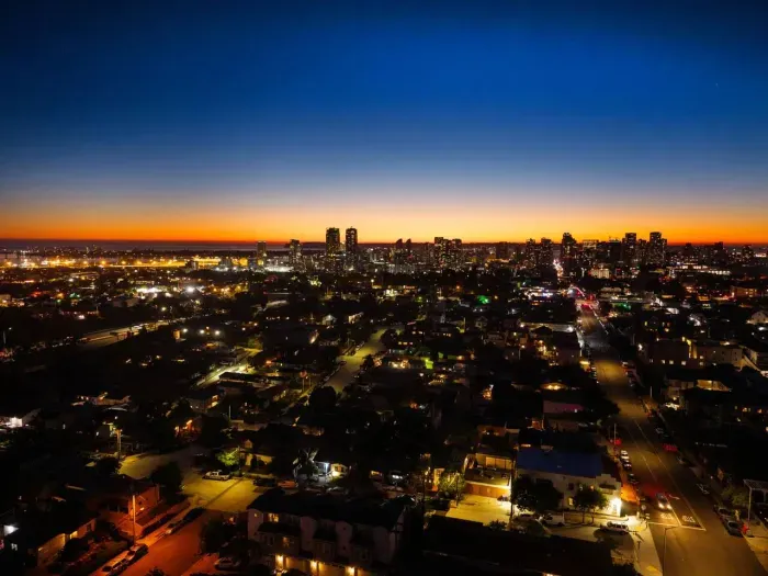 A dramatic nighttime cityscape with sparkling lights stretching across the horizon.