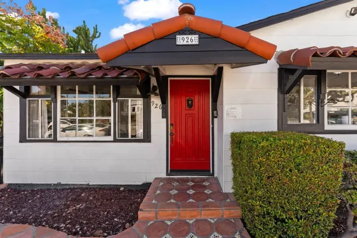 Close-up front entry view highlighting the bold red door and classic tile steps that give the home its unique personality.