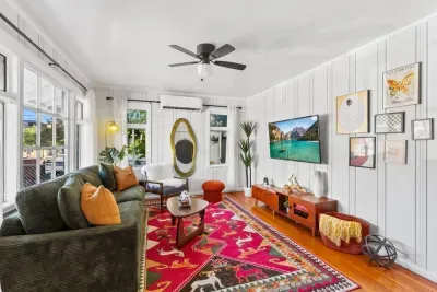A bright, inviting living room with cozy seating, bold artwork, and a vibrant patterned rug that adds warmth and character.