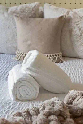 Freshly rolled towels set atop crisp linens, offering a warm welcome for arriving guests