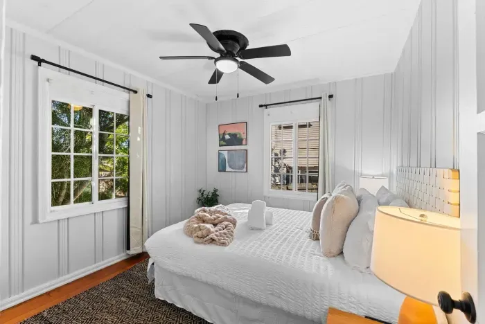 bright bedroom with crisp white linens, cozy blankets, and windows that fill the room with natural light.