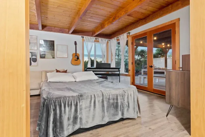 A spacious bedroom with big windows and warm natural textures throughout.