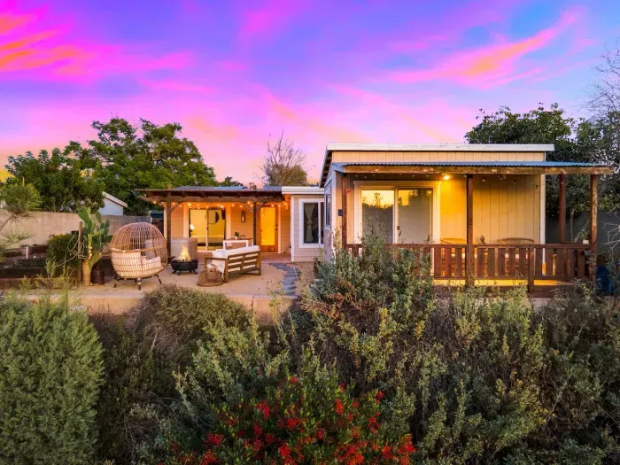 The home glows at sunset, surrounded by peaceful plants.