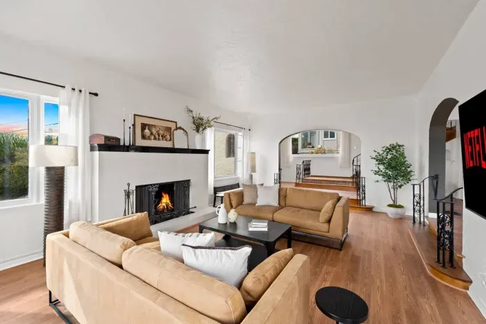 Gather around the fireplace in this sunlit living room where warmth meets elegance.