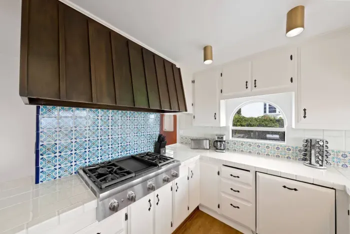Kitchen with sleek brass details and artisan tile backsplash.