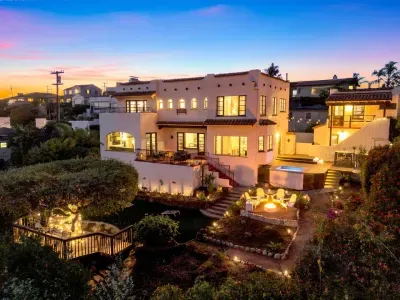 Your dream getaway begins here! A stunning Spanish-style home glowing at sunset — the perfect place to relax, laugh, and make memories under the twinkle of evening lights.