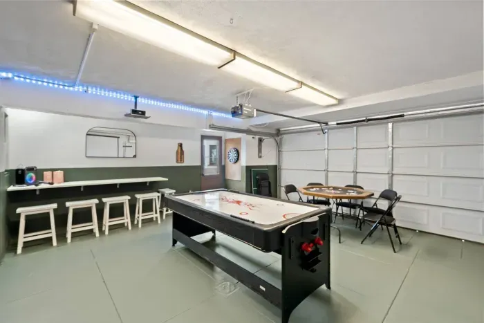 Air hockey table shines under bright lights beside bar stools and a dartboard corner