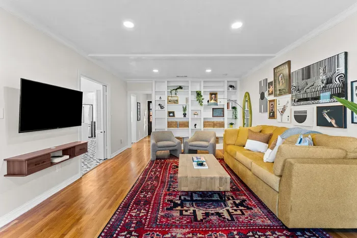 Bright, artful lounge with large sectional, built-ins, and smart TV