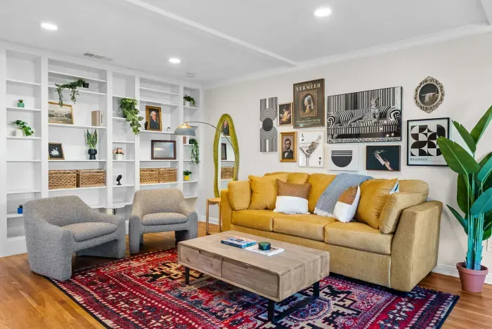 Chic living room with bold art, built-ins, vibrant rug, and cozy seating.