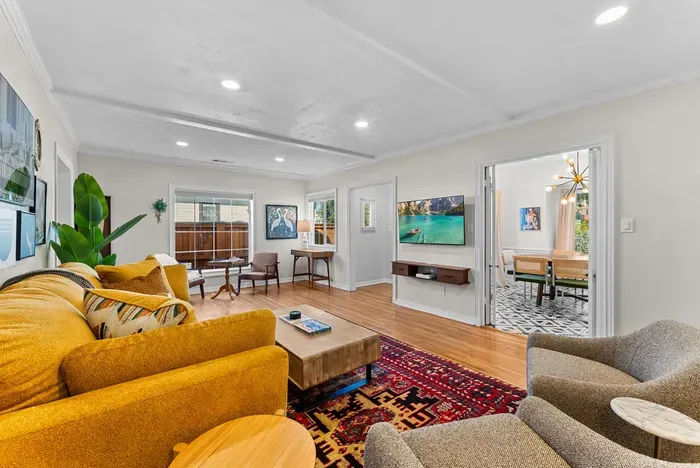 Sunny living room with smart TV, workspace, and open dining access