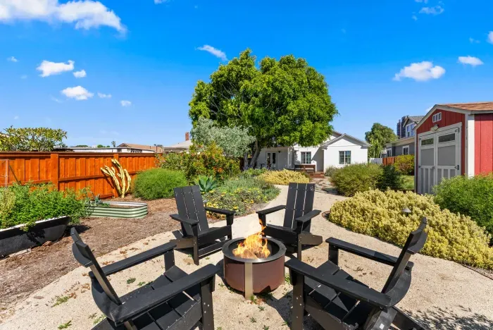 Cozy fire pit lounge in lush, private, sunlit backyard oasis