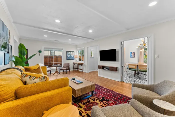 Bright lounge with TV, mid-century flair, and dining through French doors